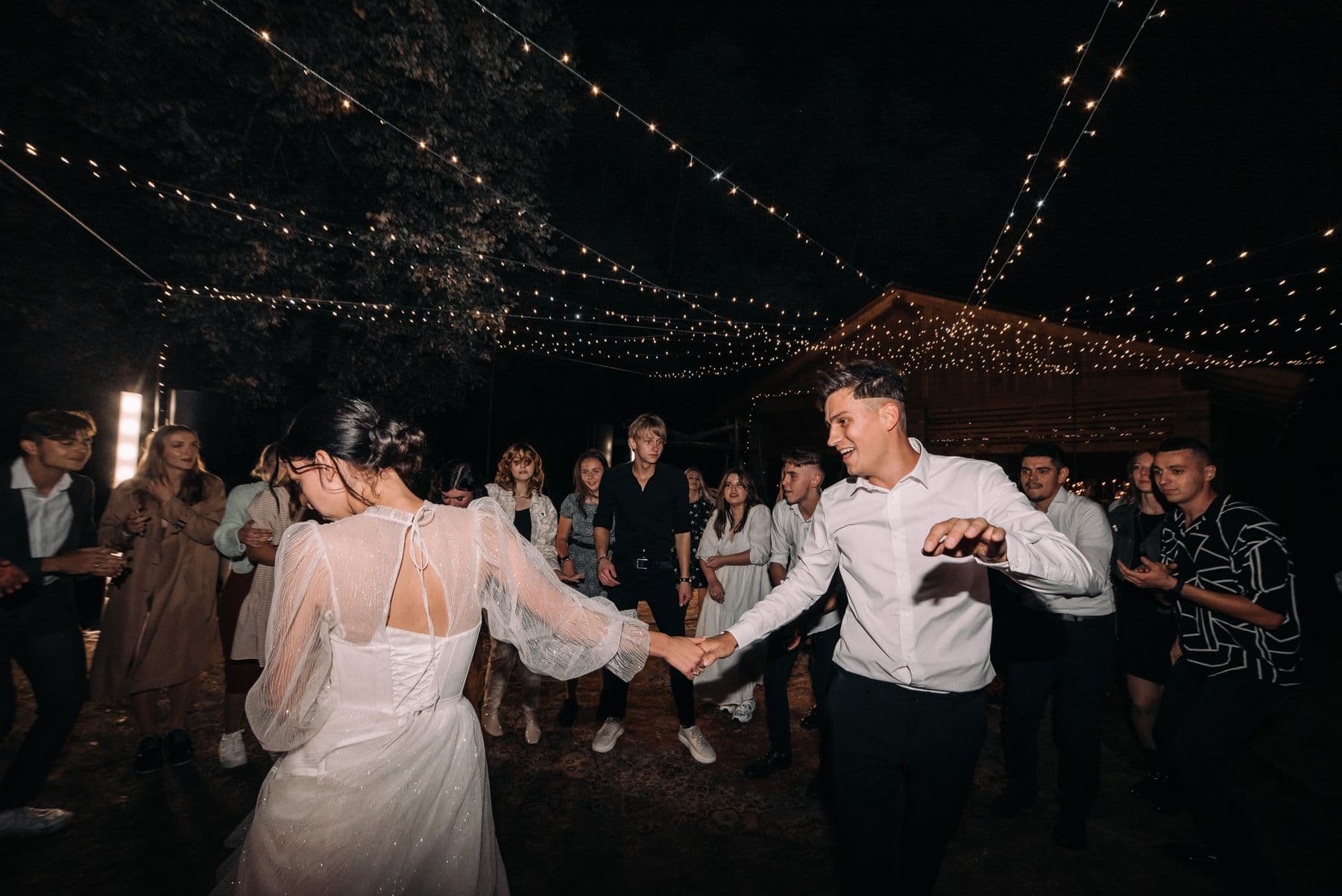 Brudepar danser tett under varme lyslenker mens kvelden senker seg