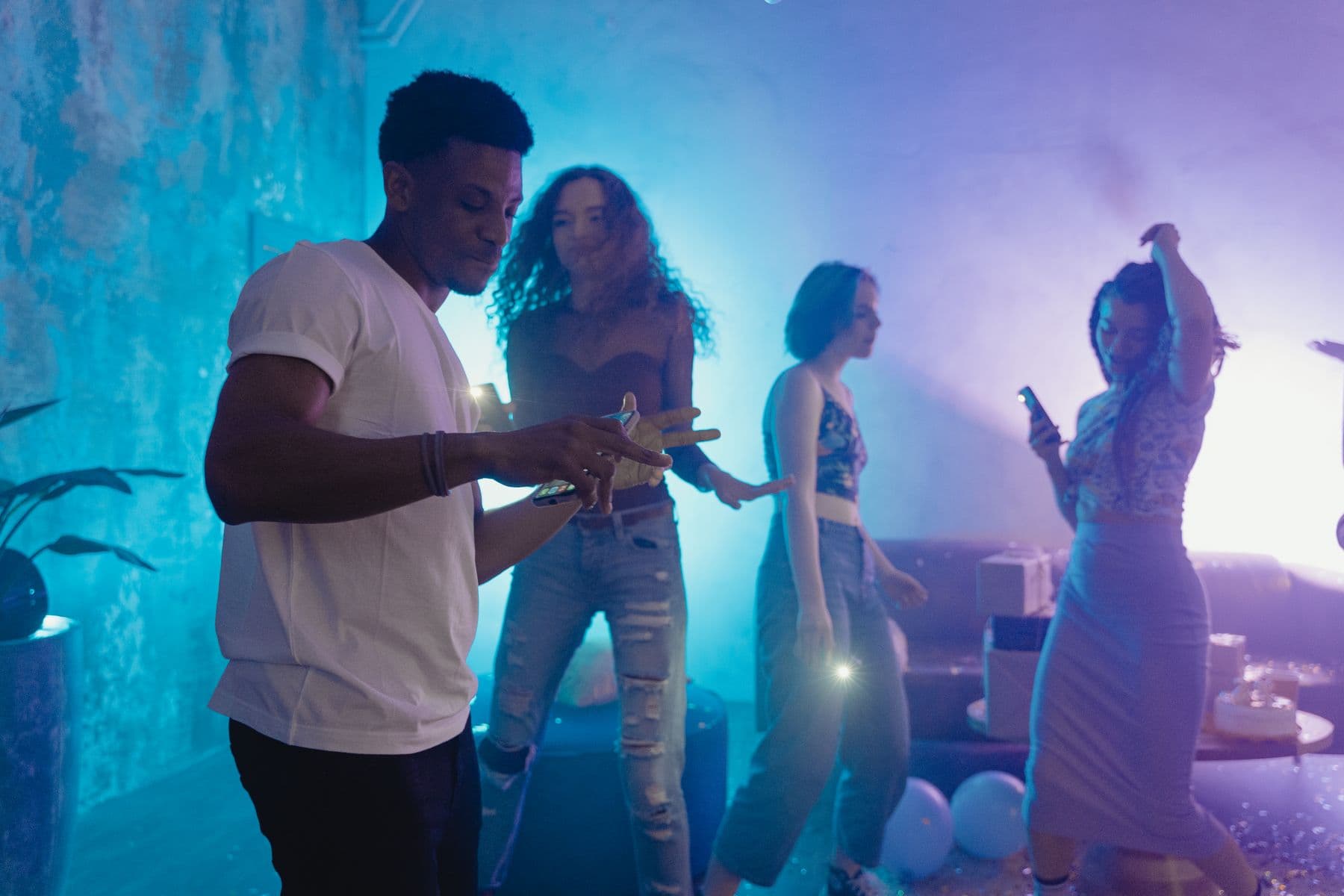 Venner danser sammen under fargerike lys på en bursdagsfest